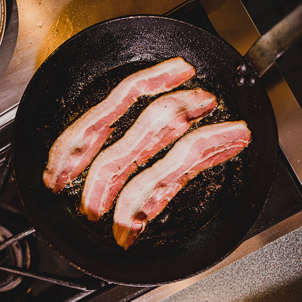 CURED Fine Meats - Maple Cured Bacon cooking in a skillet